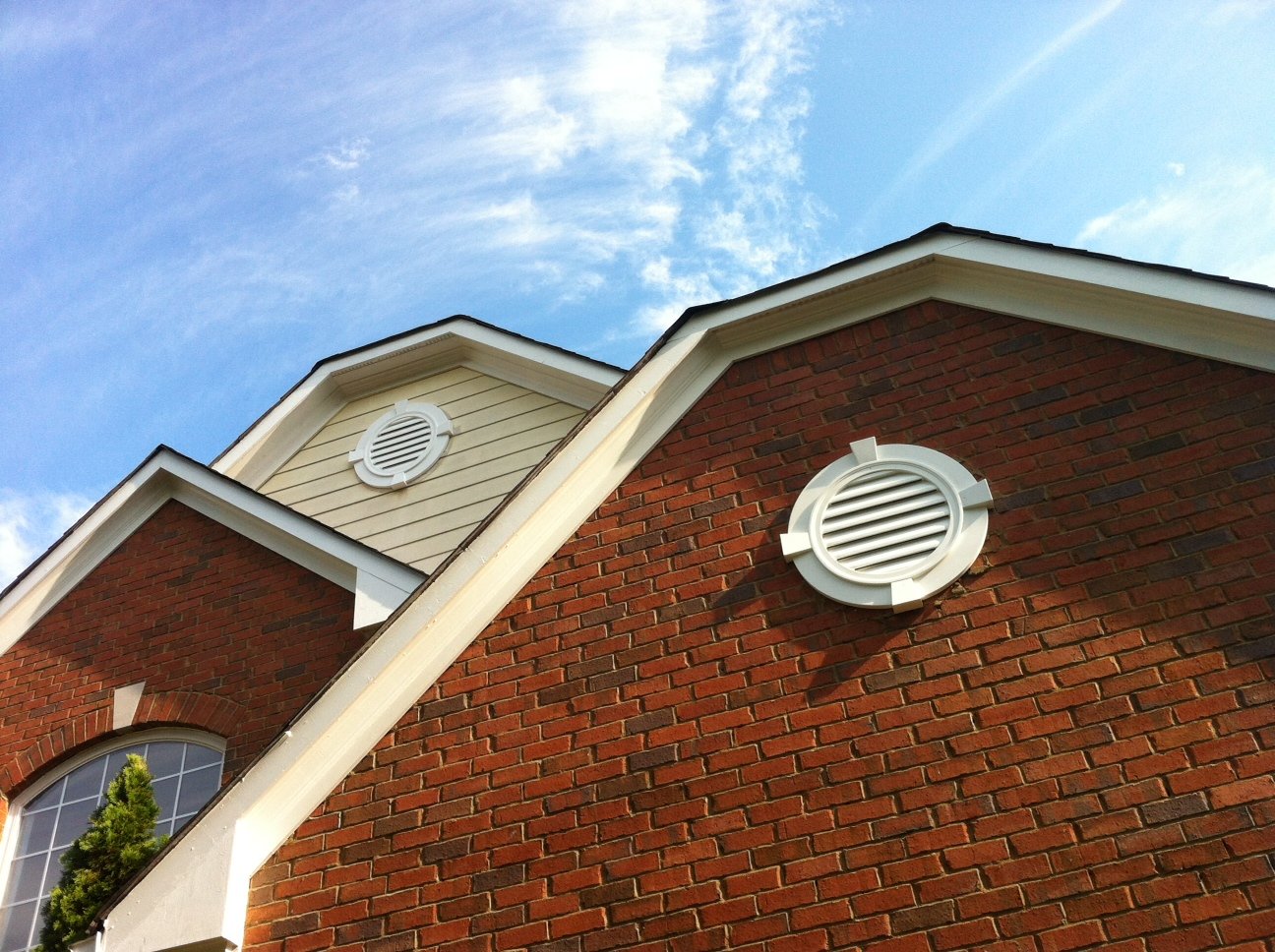 White Decorative urethane gable vents attached on brick and wood planks.