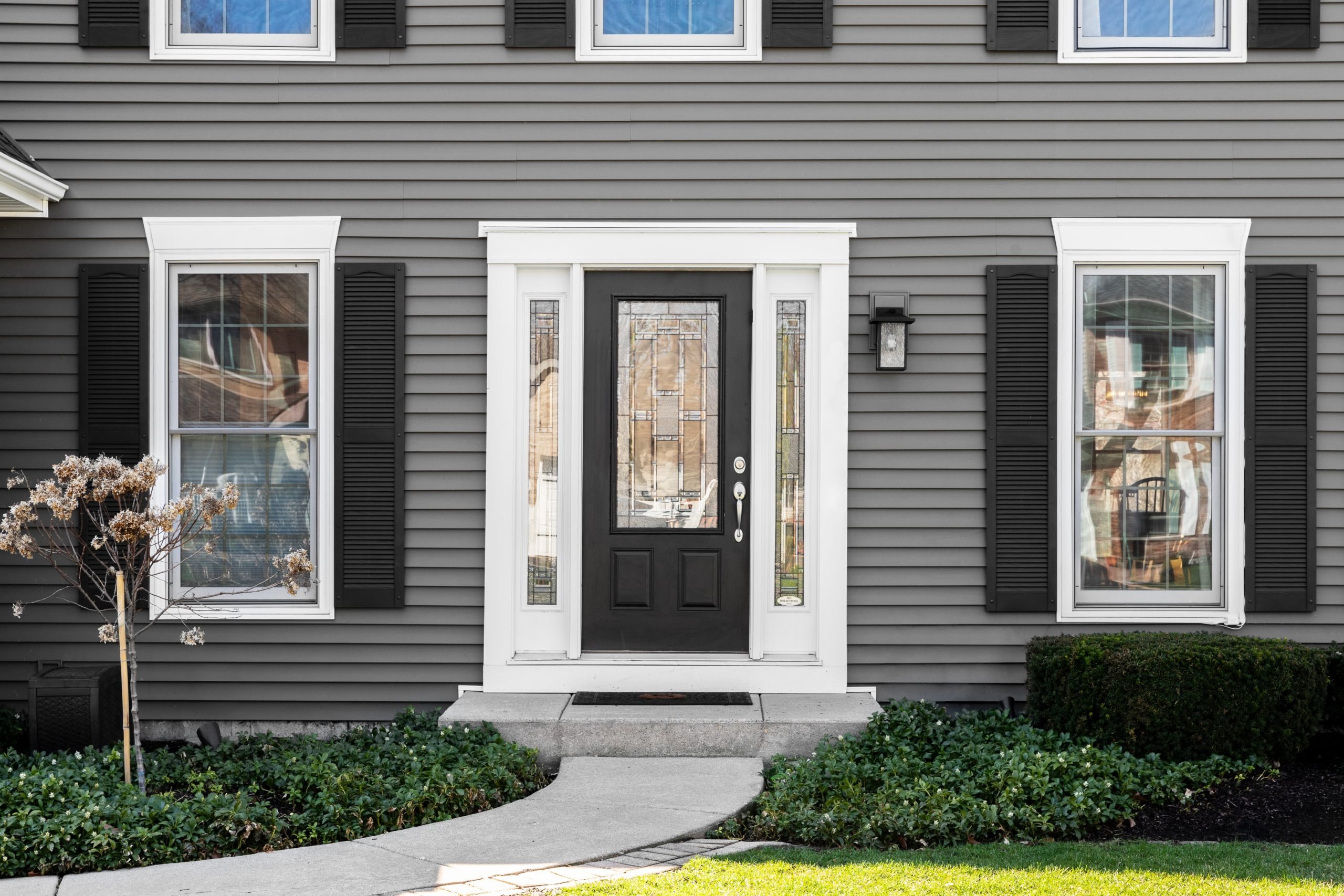 black exterior louver vinyl shutters on a house with gray siding